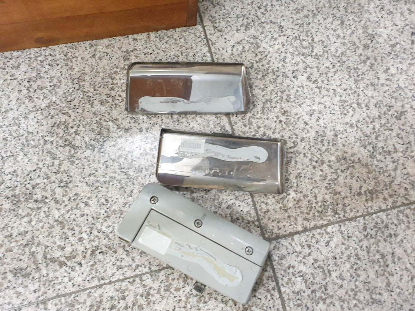 바닥에 놓인 두 개의 은색 힌지 커버와 한 개의 회색 힌지 부품