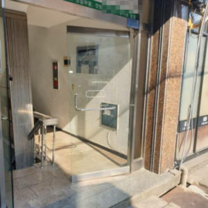 강화유리 출입문이 프레임과 H바와 함께 보이며, 문이 약간 기울어져 있습니다.
