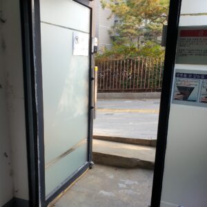 프로스트 강화유리 출입문 하단 플로어힌지 주변에 검은 오염이 보인다.